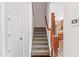 Carpeted staircase with wood railing leading to upper level, kitchen in background at 286 Sea Mist Dr, Sanford, NC 27332