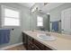 Well-lit bathroom featuring double sinks, a large mirror, and neutral-toned walls at 323 E Stratford Dr, Henderson, NC 27537