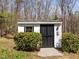 Exterior view of storage shed with black door and landscaped bushes at 323 E Stratford Dr, Henderson, NC 27537