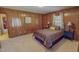 A bedroom with carpet features wood paneling, a paisley bedspread, and natural light at 382 Wimbledon Dr, Roxboro, NC 27573