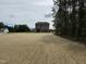 View of a large straw-covered backyard bordered by woods with newly constructed homes in the background at 4012 Kingcraig Ln, Zebulon, NC 27597