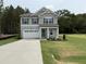 Charming two-story home with gray siding, stone accents, attached garage, and green front lawn at 4012 Kingcraig Ln, Zebulon, NC 27597