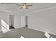 A light, carpeted bedroom with multiple doors and a ceiling fan at 4012 Kingcraig Ln, Zebulon, NC 27597