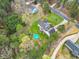 An aerial view of a home with a circular pool, a sprawling lawn, and a wooded perimeter, nestled in a serene neighborhood at 402 Womble Dr, Lillington, NC 27546