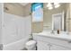 Bright bathroom with a white tub, toilet, vanity, and a window with blue curtains at 402 Womble Dr, Lillington, NC 27546