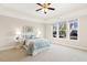 Bright bedroom with tray ceilings, a ceiling fan, and large windows offering plenty of natural light at 405 Daisy Grove Ln, Holly Springs, NC 27540