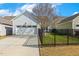 Exterior showcasing a two-car garage, driveway, fenced backyard, and tidy landscaping at 405 Daisy Grove Ln, Holly Springs, NC 27540