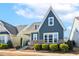 Beautiful two-story home with stone accents, blue siding, and a landscaped front yard with lush greenery at 405 Daisy Grove Ln, Holly Springs, NC 27540
