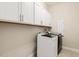 Well-lit laundry room with white cabinets above washer and dryer on light tile flooring at 405 Daisy Grove Ln, Holly Springs, NC 27540