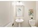 Cozy powder room with pedestal sink, toilet, decorative art, and framed mirror at 405 Daisy Grove Ln, Holly Springs, NC 27540