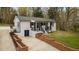 Beautifully renovated exterior of home featuring a brick retaining wall and covered front porch at 4509 Alamance Baptist Church Loop, Burlington, NC 27215
