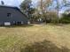 Large grassy backyard of gray home with trees and metal fence in background at 5486 B Us Hwy 301, Four Oaks, NC 27524