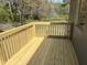 New deck overlooking backyard with lush trees and landscaping with wooden railing at 5486 B Us Hwy 301, Four Oaks, NC 27524