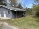 Gray home featuring covered porch with wood posts and railing, steps, yard and pond at 5486 B Us Hwy 301, Four Oaks, NC 27524