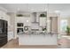 Modern kitchen with white cabinets, stainless steel appliances, a large island, and stylish pendant lighting at 715 White Oak Pond Rd, Apex, NC 27523