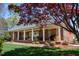 Charming brick home featuring a full, covered front porch with white columns and manicured landscaping at 805 Lee St, Gibsonville, NC 27249