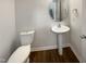 Modern half-bathroom with pedestal sink, round mirror, and wood-look flooring at 106 Canvasback Dr, Durham, NC 27704