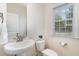 Bright bathroom featuring a pedestal sink, toilet, and window with natural light at 110 White Burley Ct, Durham, NC 27703