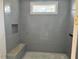 The shower features sleek grey tiles, a built-in bench, and a niche for storage, plus natural light at 1216 Barcroft Pl, Raleigh, NC 27615