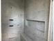 Shower featuring marble-tiled walls, built-in niche and modern fixtures at 1216 Barcroft Pl, Raleigh, NC 27615