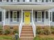 Close up of front porch and yellow front door, brick stairs with white railings, and well maintained landscaping at 2032 Stoneglen Ln, Raleigh, NC 27603