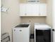 Laundry room featuring modern washer and dryer units with overhead storage cabinets and folding area at 208 Evanview Ct, Apex, NC 27523