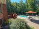 Backyard pool area with patio, orange umbrella, and mature trees in the background at 2440 Helena Moriah Rd, Timberlake, NC 27583