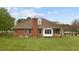 A large backyard with a brick home, surrounded by lush greenery and mature trees at 2563 Millbrook Dr, Haw River, NC 27258