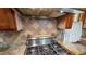 A stainless steel stovetop and hood with beautiful granite countertops and decorative tile backsplash at 308 College St, Oxford, NC 27565