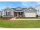 Charming home featuring a stone facade, well-manicured lawn, and inviting brick walkway at 312 Providence Creek Dr, Fuquay Varina, NC 27526