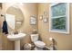 Charming half-bathroom with pedestal sink, decorative mirror, and a window offering natural light at 45 Pebble Creek Dr, Franklinton, NC 27525
