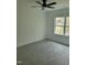 A carpeted bedroom with a ceiling fan and a window overlooking a wooded area at 5710 Russell Rd, Durham, NC 27712