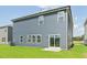 Rear exterior view featuring sliding glass door, green grass, and contemporary design with large windows and gray siding at 601 White Birch Ln, Angier, NC 27501