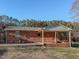 Back view of brick home featuring a cozy covered porch and landscaping at 604 Orange Factory Road, Bahama, NC 27503