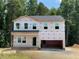 Two-story home with a two-car garage and a covered front porch, surrounded by lush trees at 62 Atherton Circle, Angier, NC 27501
