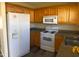 Functional kitchen featuring wood cabinets, white appliances, and ample countertop space for meal preparation at 70 Ariel St, Lillington, NC 27546