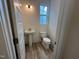 Bright powder room featuring a pedestal sink, toilet, and wood-look flooring at 766 Old Station Pointe, Angier, NC 27501