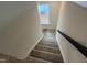 Carpeted stairs with dark wood handrail and white risers lead to the upper level of the house at 766 Old Station Pointe, Angier, NC 27501