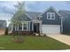 Charming single-Gathering home with manicured lawn, dark blue siding, and a young tree in the front yard at 771 Old Station Pointe, Angier, NC 27501