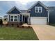 Charming single-Gathering home showcases a two-car garage, dark blue siding and manicured front lawn at 771 Old Station Pointe, Angier, NC 27501