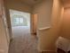 Hallway with view into a carpeted bedroom with large windows, leading to a stairway with white trim at 771 Old Station Pointe, Angier, NC 27501