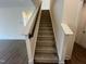 A carpeted staircase with a white banister, leading to the upper level of the home at 771 Old Station Pointe, Angier, NC 27501