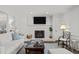Well-lit living room with white brick fireplace, TV, and cozy seating with views of the backyard at 8000 N Bridgewater Ct, Raleigh, NC 27615