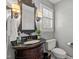 Charming powder room with dark wood vanity, decorative mirror, and neutral wall paint at 8000 N Bridgewater Ct, Raleigh, NC 27615