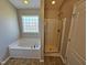 Well lit bathroom features a soaking tub with tile flooring and a glass enclosed shower at 1036 Steelhorse Dr, Fuquay Varina, NC 27526