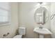 Stylish half bathroom with a pedestal sink, toilet, and elegant mirror at 104 Low Country Ct, Morrisville, NC 27560
