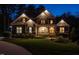 A charming house with illuminated windows and landscape lighting at dusk at 107 Bella Casa Way, Clayton, NC 27527