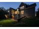 Home's exterior at dusk showcasing well-lit deck, lush lawn, and architectural details at 107 Bella Casa Way, Clayton, NC 27527