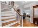 Inviting foyer with hardwood floors, white and wood staircase, and a glimpse into the cozy living room at 108 Birdie Ct, Rocky Mount, NC 27804