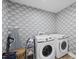 Clean laundry room with decorative wallpaper, washer, dryer, and ironing board at 111 Kim Bark Path, Garner, NC 27529